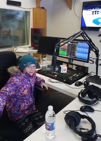 young girl sitting at microphone in local radio station