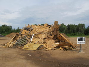 pile of wood waste with sign in front sign text is Wood