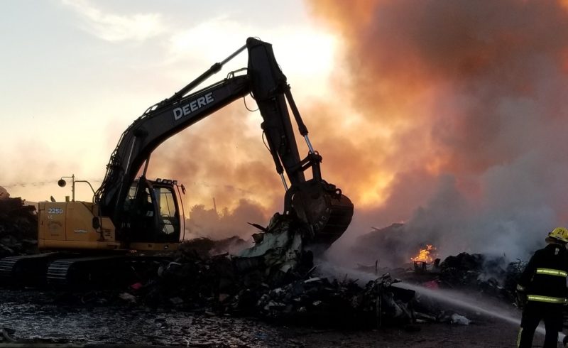 excavator moving materials and fire fighter spraying water